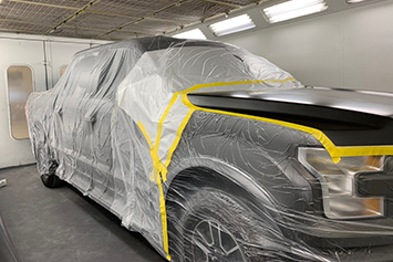 Car all taped up in a paint booth ready for painting