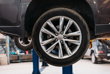 Small image of Wheel alignment showing the tire of a car up on a hoist