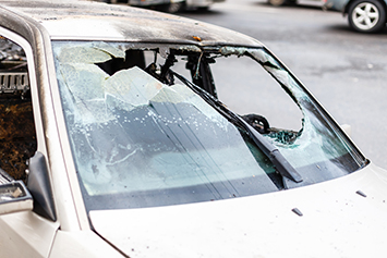 Compact car with a large hole in the windshield and some roof damage